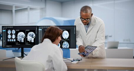 Two Medical Technicians Carefully Study Brain MRI Scans Together