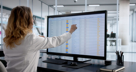 Woman Coding Financial Accounts Using Computer And Spreadsheet