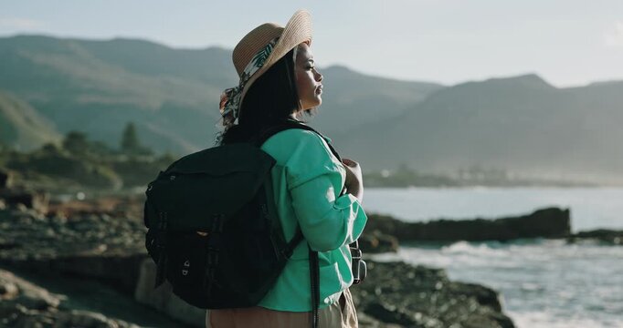 Woman, thinking and summer holiday by beach with backpack, tourist sightseeing and hat for vacation. Female person, travel adventure and outdoor by ocean with reflection, bag and island exploration.