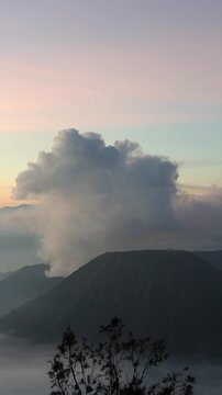 Vertical B-Roll of Gunung Batok Cinder Cone with Mount Bromo Eruption at Sunrise | King Kong Hill, East Java, Indonesia