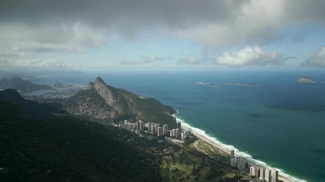 High altitude aerial looking down at Morro Dois Irm&atilde;os, Rocinha favela, and S&atilde;o Conrado next to turquoise ocean. Shot at 4K Apple ProRes 422.