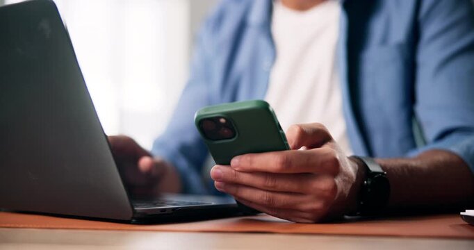 Phone, laptop and hands of businessman in office with texting, email or chatting on mobile app on break. Technology, computer and person with cellphone for typing, social media or online at startup.