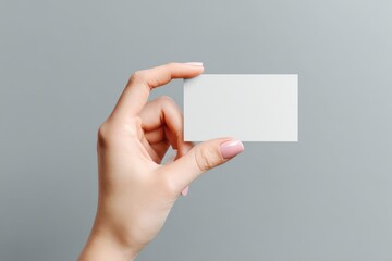 Fototapeta premium Hand holding a blank card against a gray backdrop
