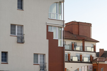 Obraz premium Modern residential buildings with balconies and large windows, showcasing a blend of brick and stucco architectural styles in an urban setting