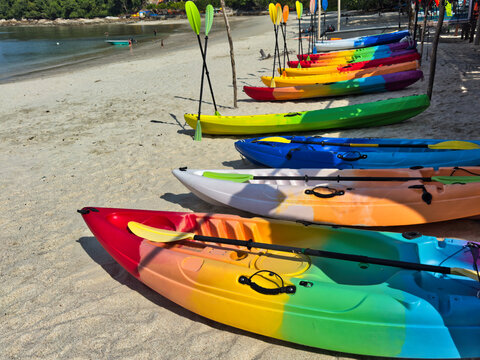 Colourful canoes lined up along the sandy shore of Teluk Nipah Beach, Pangkor Island, ready for water activities under clear blue skies and calm tropical waters