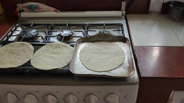 Placing a handmade tortilla on a hot griddle