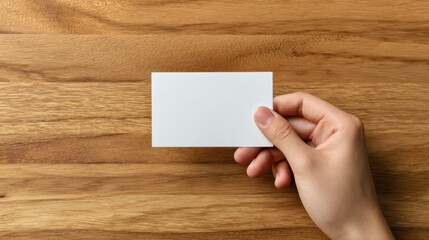 Obraz premium Blank card held in a gentle hand on wooden table