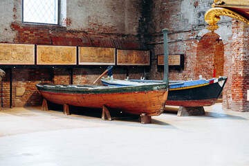 Obraz premium Wooden boats on display in an old brick building with stone walls in a historical location