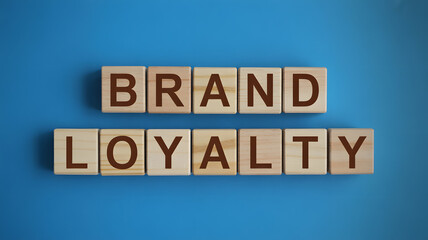 Close up view of wooden block letters forming the phrase brand loyalty on a bright blue surface
