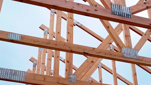 Wooden roof truss framework under construction with metal connector plates and beams