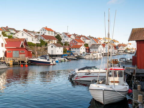 Harbour channel in Gullholmen, Bohusl&auml;n, Sweden, with moored boats in foreground and waterfront houses on H&auml;rman&ouml; island
