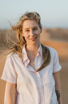 beautiful woman with windblown blonde hair in desert sand dunes
