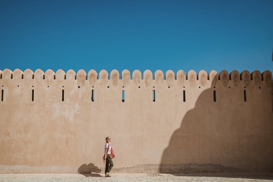 caucasion woman walks along old fort wall in the Middle East.