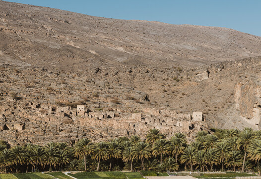 Ruins of Ghul old village on mountainside in Oman with date palms