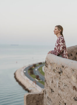 Woman takes in view high above Mutrah and the Gulf of Oman
