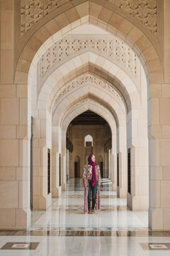 Caucasian woman stands along islamic style arches in Mosque