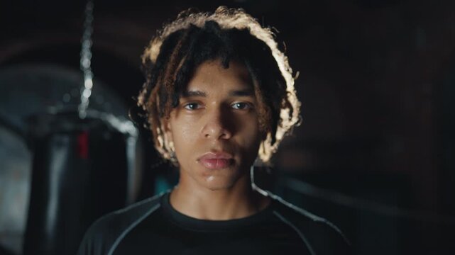 Athletic man looking at camera, portrait of african sportsman in gym, fitness. Handsome young male person do combat sports for stay strong, developing endurance and muscles, motivated sportsperson