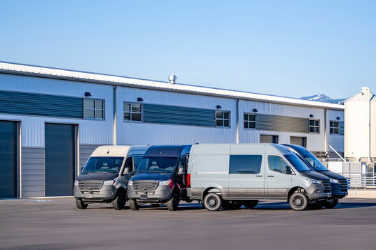 Industrial standard cargo mini vans standing on the warehouse parking lot waiting for the next loads