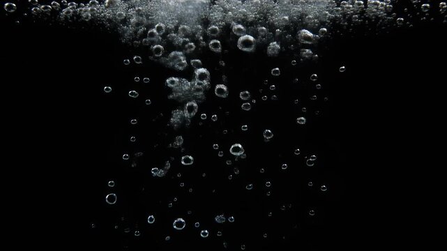 Close-up of numerous air bubbles rising through dark water, creating a dynamic and effervescent visual effect.