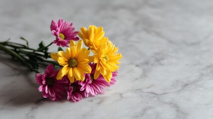 Obraz premium Close-up of a bunch of flowers on a white marble surface. the flowers are a mix of yellow and pink daisies with green leaves.