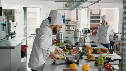 Professional chef adding grated parmesan cheese on food in pan, cooking culinary recipe meal in...
