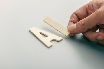 Hand arranging wooden AI letters on clean background