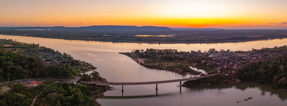 Drone perspective of Pak Kading at dusk, where warm orange and pink skies illuminate the river landscape and rural surroundings of Bolikhamxay Province.