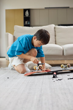 A boy fixing his skateboard at home