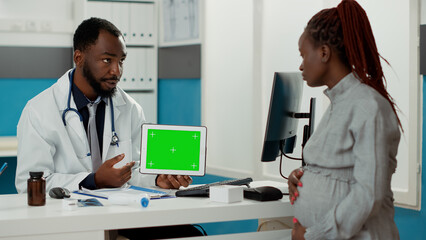 Physician holding digital tablet with horizontal greenscreen at consultation with pregnant woman....