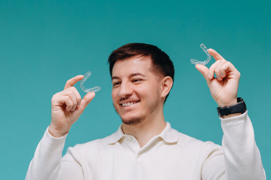 Smiling man comparing clear dental aligners for orthodontic treatment and at-home teeth straightening