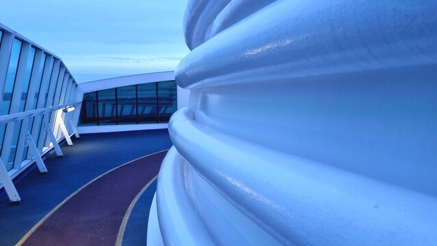 A technical area with ventilation and pipes on the open deck of a ferry ship with a treadmill separated by a colored coating. 