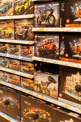 Fototapeta premium Chemnitz, Germany - March 14, 2026: Shelves are filled with multiple Lego set boxes showcasing cars, trucks, and buildings. Customers browse through the options in a busy store