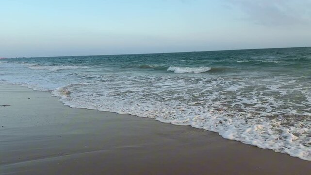 Original 4K 120fps high frame rate (HFR) wide shot of gentle ocean waves breaking and rolling onto a peaceful sandy beach. Real-time playback, ideal for custom speed ramping.