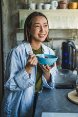 Young woman enjoying healthy breakfast in kitchen at home