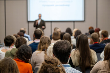 Obraz premium Audience in conference room listening to presenter on stage, professional business seminar, training and corporate meeting atmosphere.