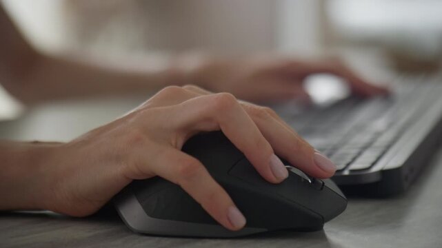 Hand using ergonomic mouse at computer desk
