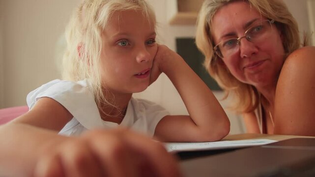 Mother and daughter study together at home using a laptop. Back to school preparation with technology and parental guidance
