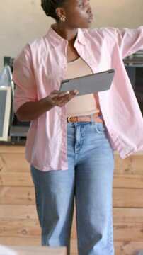 Vertical video: Glancing at menu, staff in pink top checking tablet to confirm orders at counter