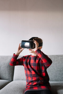 Girl sitting on the couch in the living room using Virtual Reality Glasses