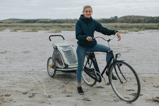 Netherlands, Schiermonnikoog, woman with bicycle and trailer on the beach