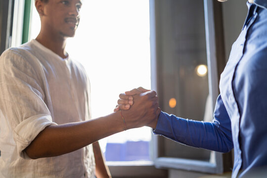 Happy young man high fiving with colleague in a cafe