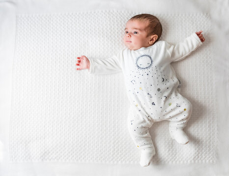Baby boy laying in bed over white blanket