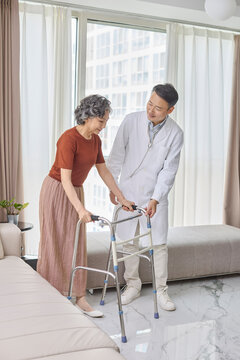 Senior woman using a walking frame under her doctor's supervision