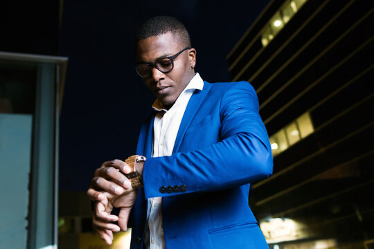 Young businessman wearing blue suit jacket and checking the time