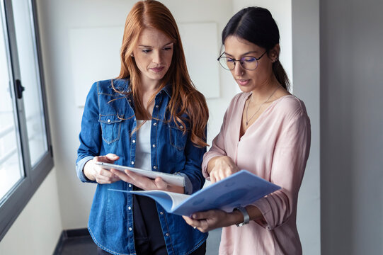 Businesswomen using digital tablet and looking at documents in the office