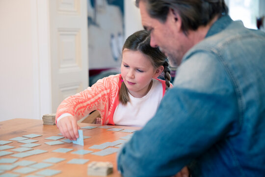 Father and daughter playing memory on table at home