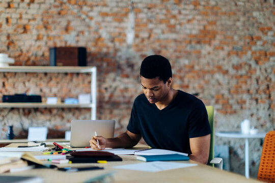 Young man sitting at table taking notes