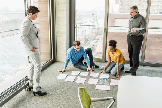 Businesspeople looking at documents on office floor