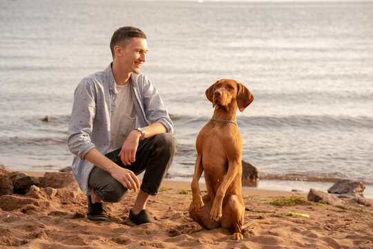 Young man with his dog at the beach during training