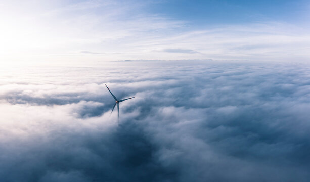Germany, Aerial view of wind turbine shrouded in clouds at dawn